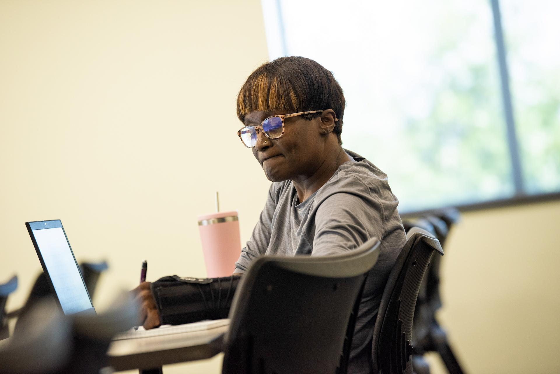 Student with arm brace takes notes during class